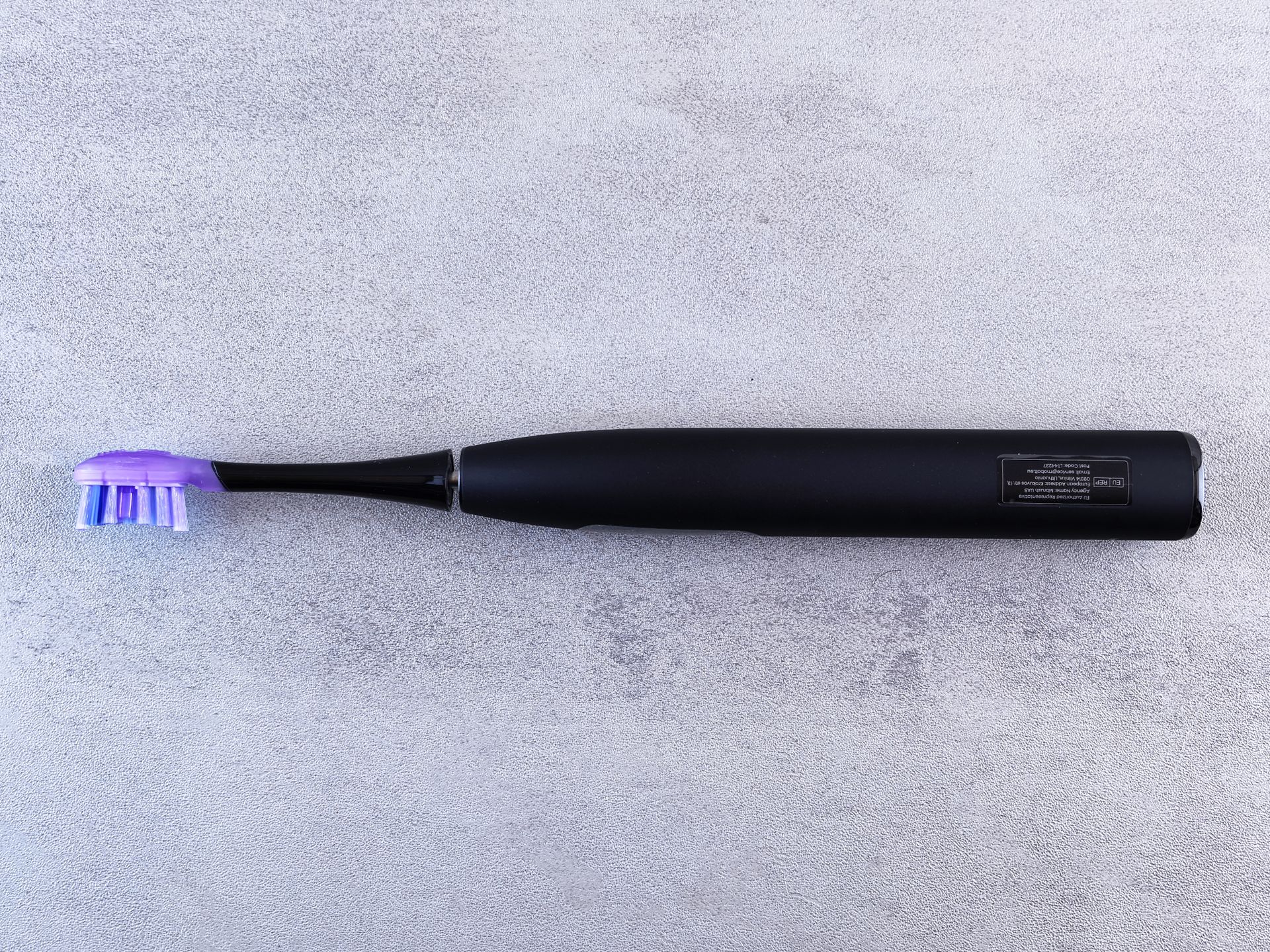 A modern electric toothbrush standing on a bathroom surface